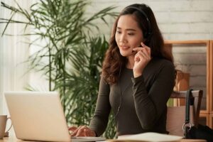 Woman virtual assistant working remotely as a remote assistant using a laptop and headset.